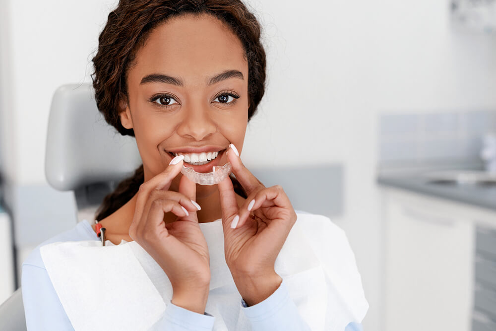 women smiling holding a clear aligner