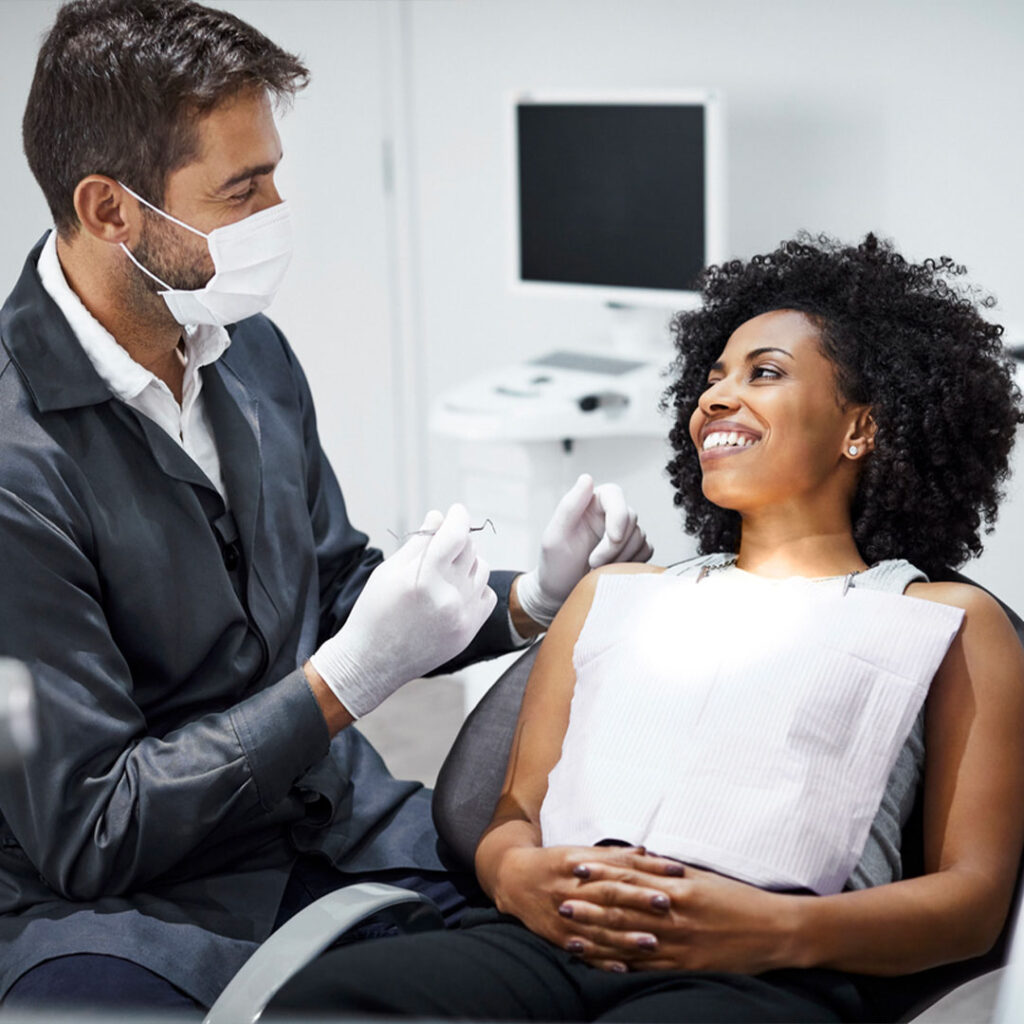 smiling female patient looking at a doctor who's ready to check her teeth